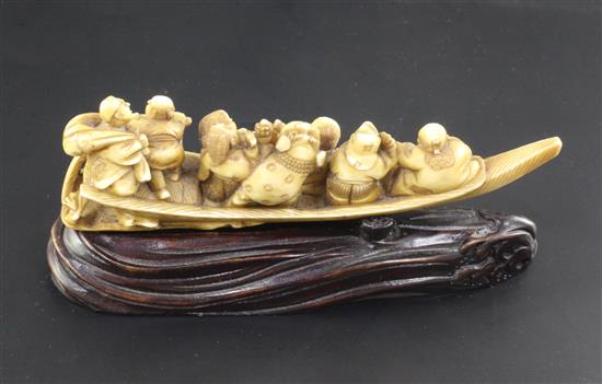 A Japanese ivory okimono of figures enjoying festivities on a boat, Meiji period, 12.3cm, wood stand